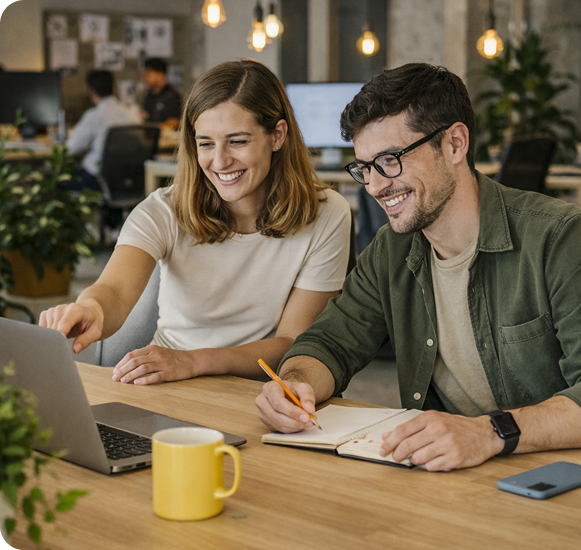 Two colleagues smiling while looking at a laptop together